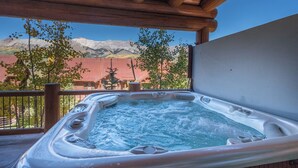 A hot tub with a wooden pergola overhead, surrounded by a wooden deck and a mountain view. - Townhomes On The Creek 119 (Mountain Village)