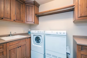 A compact kitchen with wooden cabinets, a built-in washing machine, and a sink.