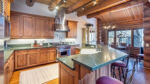 A log cabin kitchen with wooden cabinets, a large island with a sink, and a stone countertop. - Tristant 205: Ski&Hiking Access w/Hot Tub,Views | 3BR Luxury in Mountain Village (Mountain Village)