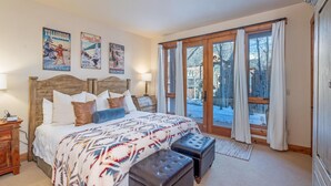 A bedroom with a large bed, wooden headboard, and a view of a snowy landscape through glass doors. - Tristant 205: Ski&Hiking Access w/Hot Tub,Views | 3BR Luxury in Mountain Village (Mountain Village)
