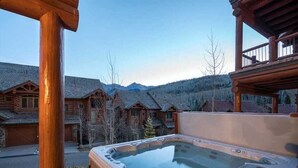 A wooden cabin with a hot tub in front, surrounded by other cabins and mountains in the background. - Villas at Tristant 205 (Mountain Village)