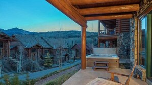 A wooden deck with a hot tub, overlooking a mountain village. - Villas at Tristant 205 (Mountain Village)