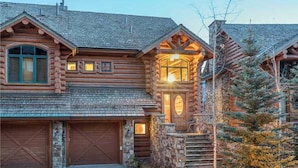A log cabin with a stone foundation, a wooden garage, and a staircase leading to a porch. - Tristant 205: Ski&Hiking Access w/Hot Tub,Views | 3BR Luxury in Mountain Village (Mountain Village)