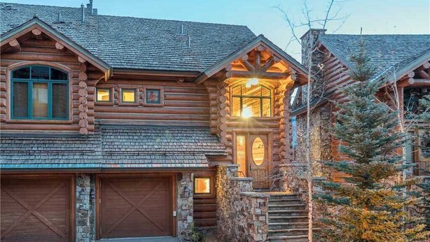 A log cabin with a stone foundation, a wooden garage, and a staircase leading to a porch. - Villas at Tristant 205 (Mountain Village)