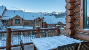 A wooden cabin with a snow-covered deck and a view of snow-covered mountains. - Spacious 4 Bedroom Villa with Ski-in Ski-out Access (Mountain Village)