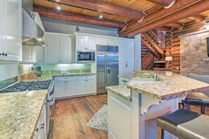 A kitchen with white cabinets, a stainless steel refrigerator, granite countertops, and a wooden floor. - Villas At Tristant 201 (Mountain Village)