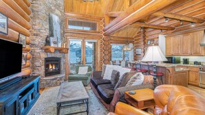 Ein Holzblockhaus-Interieur mit Kamin aus Stein, Holzmöbeln und einer Küchenzeile.
