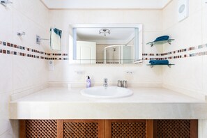 A modern bathroom with a white sink, a mirror, and a glass shower enclosure. - Alcalá Plaza (Alcalá)