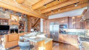 Una cocina amplia con armarios de madera, una isla central y una chimenea de piedra.