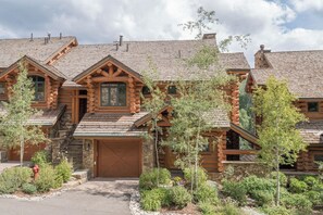 A log cabin with a stone foundation, a garage, and a landscaped front yard. - Villas At Tristant 221 (Mountain Village)