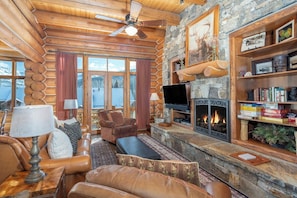 A log cabin interior with a fireplace, leather furniture, and a stone wall. - Villas At Tristant 221 (Mountain Village)