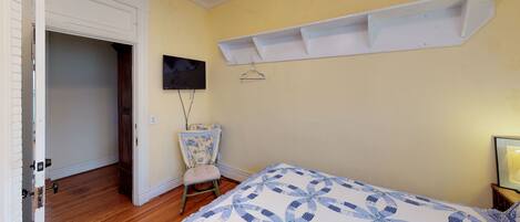 A bedroom with a bed, a chair, a television, and a shelf.
