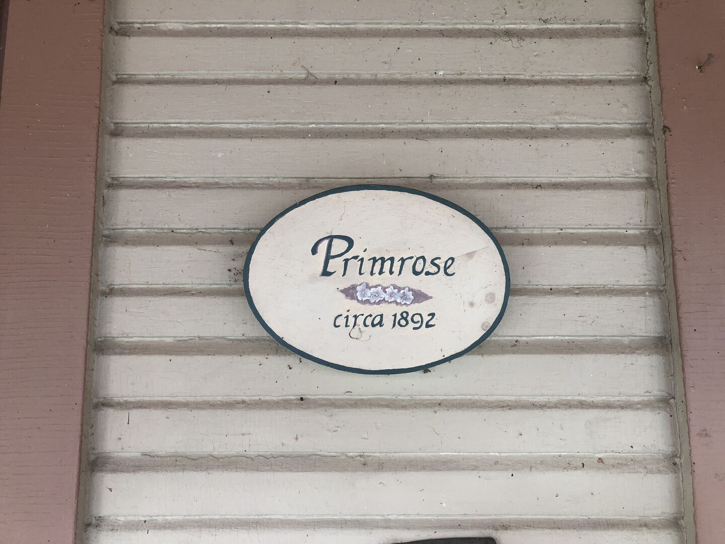 Una señal circular con el texto 'Primrose circa 1892' sobre una pared con textura.