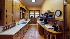 A kitchen with wooden cabinets, a marble countertop, a brick backsplash, and a clock on the wall. - Primrose Bed and Breakfast Posy Room Hocking Hills Ohio between Logan & Athens (Nelsonville)