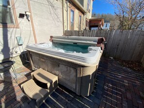 A hot tub with a stone exterior, a wooden deck, and a wooden fence in the background. - Primrose Bed and Breakfast Posy Room Hocking Hills Ohio between Logan & Athens (Nelsonville)