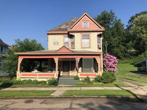 A two-story house with a porch and a small garden. - Primrose Bed and Breakfast Posy Room Hocking Hills Ohio between Logan & Athens (Nelsonville)