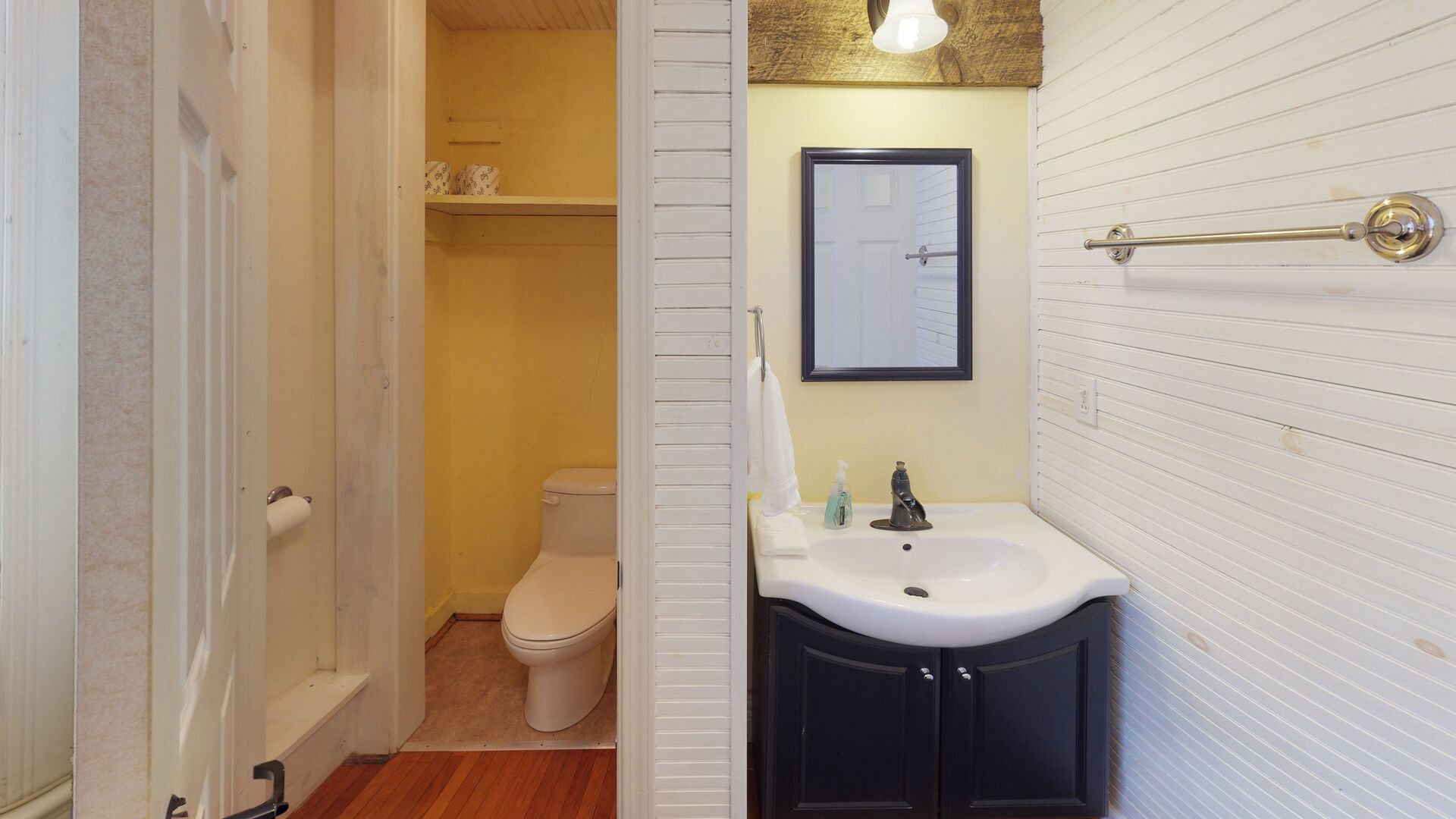 A bathroom with a toilet, a sink, and a mirror.