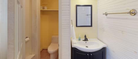 A bathroom with a toilet, a sink, and a mirror.