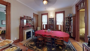 Une salle à manger avec une table ronde, des chaises, une cheminée, des étagères à livres et un globe terrestre.