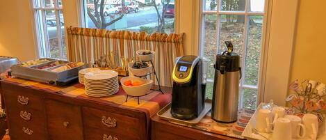 A breakfast bar with a coffee maker, a thermos, and a mug holder.