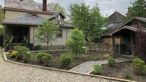 A residential property with a covered porch, a small garden area with various plants, and a wooden fence. - Primrose Path Bed and Breakfast Hocking Hills between Logan and Athens (Nelsonville)