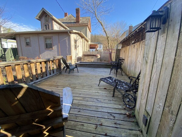 A wooden deck with outdoor furniture, including chairs and a table, surrounded by a wooden fence.