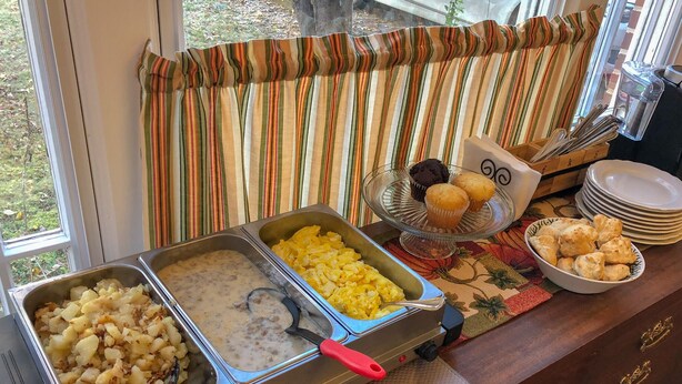 A buffet setup with various food items including potatoes, scrambled eggs, and muffins. - Primrose Path Bed and Breakfast Hocking Hills between Logan and Athens (Nelsonville)