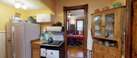 A compact kitchen with a refrigerator, stove, and wooden cabinets.