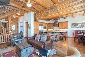 A spacious living area with a leather sofa, a wooden coffee table, and a rustic ceiling.