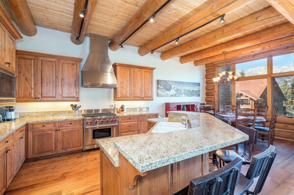 Una cocina con armarios de madera, encimeras de granito y una isla grande con asientos.