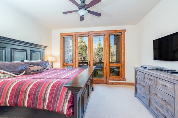 A bedroom with a bed, a dresser, a television, and a sliding glass door leading to a balcony.