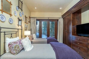 A hotel room with two beds, a television, a large wooden cabinet, and a view of the outdoors.