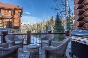 Une cabane en bois dotée d’un balcon, de meubles en osier et d’un barbecue.