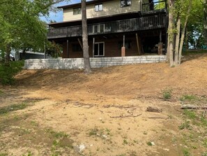 A two-story house with a balcony, surrounded by trees and a dirt area. - THE NEST getaways&gatherings, beach/lake sleeps 20+ (Greenville)