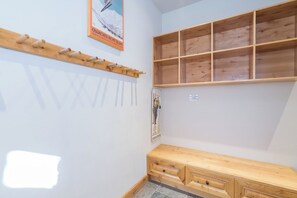 A room with a wooden bench, a coat rack, and a shelf unit.