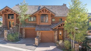 A log cabin with a stone foundation, a large garage, and a prominent chimney. - Villas At Tristant 215 (Mountain Village)