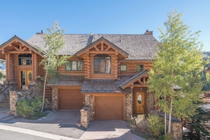 Une cabane en rondins avec des fondations en pierre, un grand garage et une cheminée imposante.