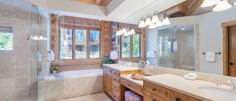 Un baño moderno con un espejo grande, armarios de madera y una cabina de ducha con mampara de vidrio.
