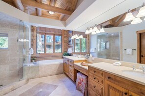 A modern bathroom with a large mirror, wooden cabinets, and a glass shower enclosure.