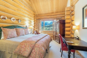 Une chambre aménagée dans un chalet en rondins, avec un lit, un bureau et une commode.