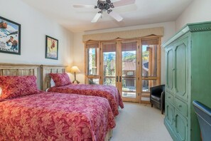 A bedroom with two beds, a ceiling fan, a green cabinet, and a view of the outdoors.