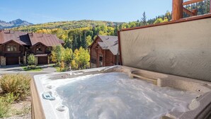 A hot tub with a view of a mountain and a wooden cabin. - Villas At Tristant 215 (Mountain Village)