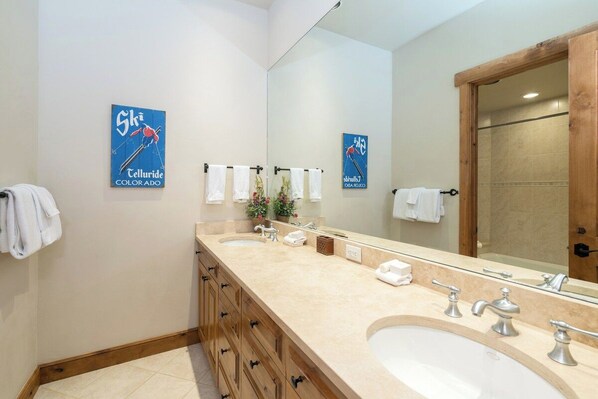 A bathroom with two sinks, a large mirror, and towels hanging on a rack.
