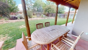 Eine Terrasse im Freien mit einem Holztisch und -stühlen, umgeben von einem Holzzaun und einem Rasen.