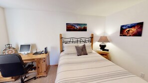 A bedroom with a bed, a desk with a computer, a lamp, and two paintings on the wall. - Arena Roja ~ 2279, Southwest 4 bedroom, 2.5 Bathroom, Pet Friendly with Private Hot Tub (Moab)
