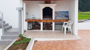 A patio with a wooden pergola, a sink, a barbecue grill, and a painting of a snowy landscape.