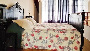A bedroom with a bed, a nightstand, a lamp, and a window with curtains.