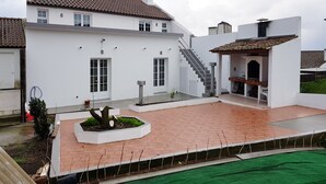 A modern house with a tiled roof, a covered patio, and a staircase leading to a second floor.