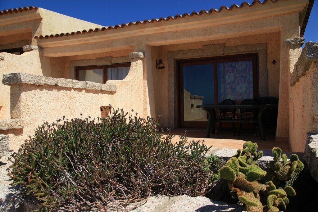 A building with a stucco exterior, a tiled roof, and a patio area with a table and chairs.