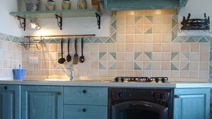 Et køkken med turkise skabe, en gasblus og et flisebeklædt backsplash.